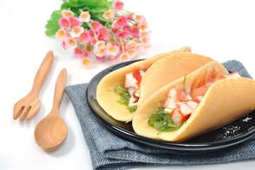 Pancakes with ham seaweed salad on gray napkin with wooden table