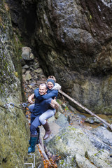 couple of hikers climbing on safety cables in a gorge above the