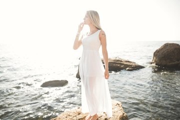 Fototapeta na wymiar portrait of young woman posing near sea, wearing a dress