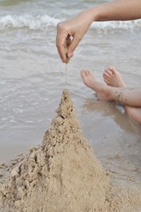 Hand drop a wet sand to made a sand castle.