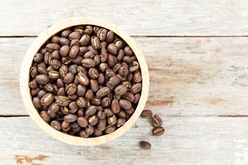roasted peaberry coffee bean in bowl on wooden background.
