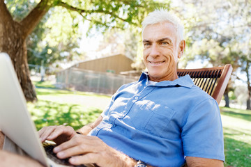 Senior man with notebook sitting in the park