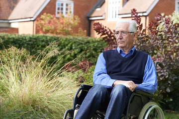 Depressed Senior Man Sitting Outdoors In Wheelchair