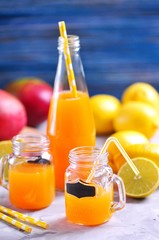 Delicious lemon mango juice in jar and bottles with straws.