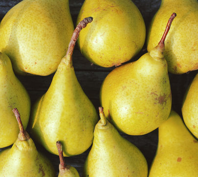 Fresh green pears against an old textural wooden surface, close up. Autumn harvest of pears