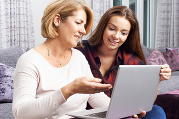 Teenage Daughter Showing Mother How To Use Laptop Computer