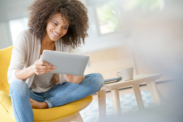 Mixed-race woman websurfing on digital tablet at home