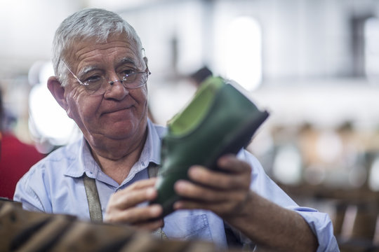 Shoemaker looking at shoelace in workshop - Powered by Adobe