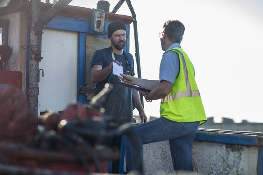 Fisherman on trawler talking to inspector