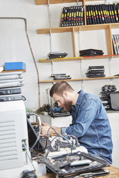 Worker in computer recycling plant removing accus from laptop