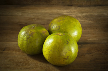 Tangerine three balls placed on a wooden table low key light.