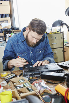 Worker in computer recycling plant removing accus from laptop