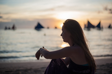 A girl sits on the beach on the island of Boracay