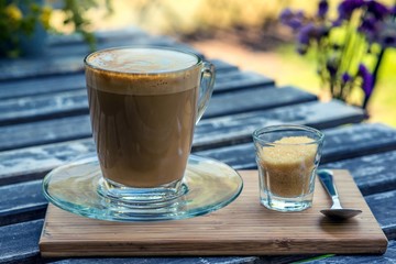 hot fresh coffee in see through glass with sugar on wood table