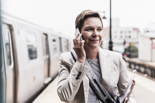 Mature woman using smart phone at commuter train station