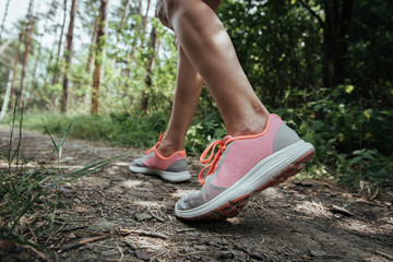 Close-up of female hiker in sport shoes traveling through natural park. Vacation, tourism and discovery concept.