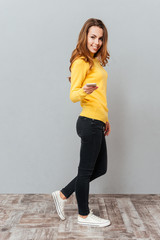 Happy smiling woman in yellow sweater with mobile phone