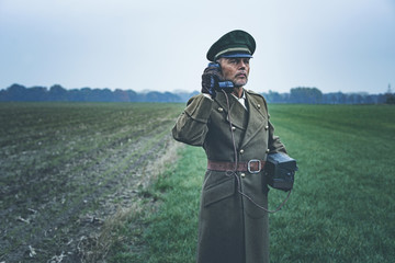 Vintage 1940s military officer calling with field phone while st