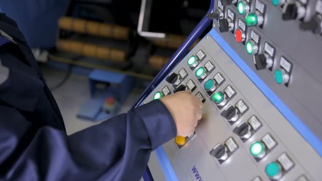 Employee operates industrial panel with control buttons at a industrial plant. HD.