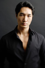 Man in black shirt, standing against black background
