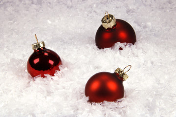 Rote Christbaumkugeln im Schnee