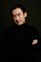 Fototapeta premium Man looking at camera, arms crossed, black background