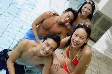 Young adult couples in swimming pool, smiling at camera, portrait