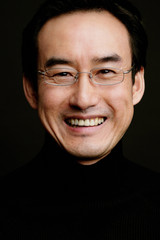 Man with glasses, smiling, head shot, black background