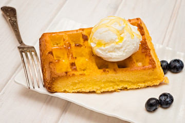Belgium waffles with blueberries  and ice cream on top on wooden table, selective focus