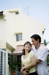 Fototapeta premium Couple standing in front of house, embracing
