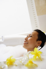 Obraz na płótnie Canvas Woman in bathtub, smiling, looking away