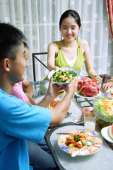Naklejka premium Young woman passing food to family members