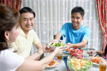 Mother and son passing food to each other at dining table