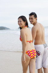 Couple on beach, looking over shoulder at camera