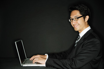 Businessman wearing glasses, with laptop, smiling at camera