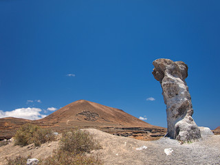 Volcanic red hillsides and wind erosion artifacts on the background of deep blue sky with white...