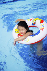 Girl in swimming pool using inflatable ring