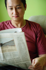 Man sitting, reading newspaper