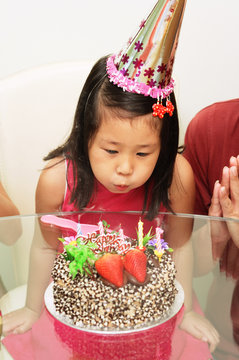 Girl blowing out birthday cake