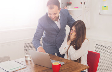 Businessman supervising his female assistant's work on laptop co