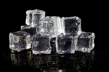 ice cubes reflection on black table background.