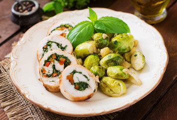 Chicken rolls with greens, garnished with stewed Brussels sprouts, apples and leeks on plate.
