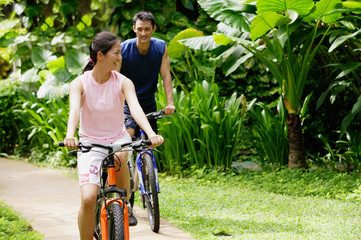 Couple cycling together through a park