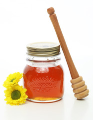 Honey jar and wooden stick with flowers on white background. Natural pharmacy.