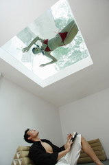 Man looking at woman in swimming pool through the skylight