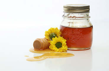 Honey jar and wooden stick with flowers on white background. Natural pharmacy.