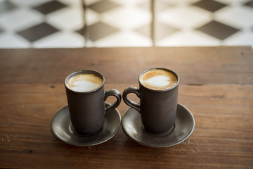 Hot latte art with  black glass on wooden table