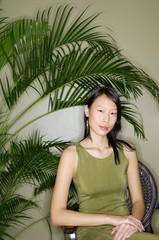 Woman sitting next to plant, looking at camera