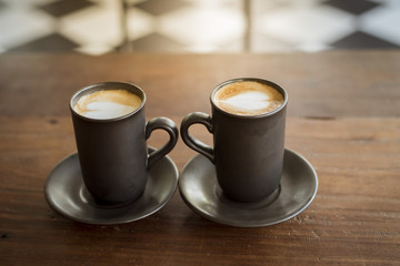 Hot latte art with  black glass on wooden table