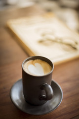 Hot latte art with  black glass on wooden table